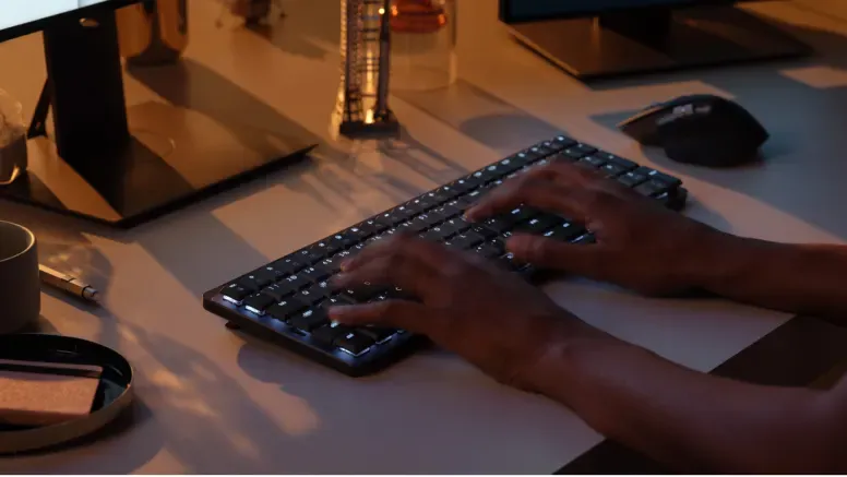 Keyboard in use on desk, dark room with warm light